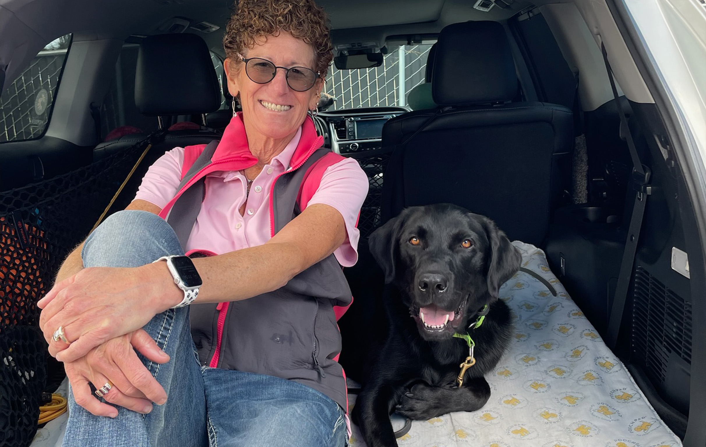 Woman and service dog sitting in the back of a SUV